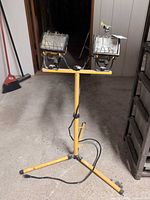 Full view of yellow tripod stand with two lamp heads and cord