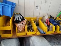 Overall view of yellow organizer bins containing gloves, locking pliers, drill bits, knives, blue bin visible
