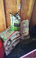 Grass seed, top soil, and fertilizer bags stacked against shed wall