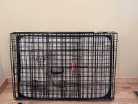 folded black wire dog crate with pad visible inside