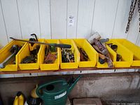 Overall view of six yellow bins lined on shelf containing mixed hand tools