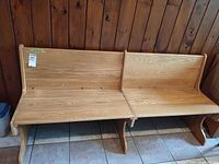 Full view of oak church pew bench against wood panel wall