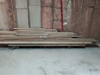 pallet of long unfinished wood planks against wall