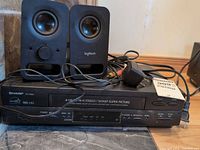 Overall lot showing Sharp VC-H960 VCR with Logitech speakers, adapter and cables
