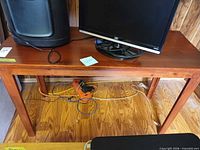 Front view of the rectangular brown solid wood table with monitor and speaker (not included) on top