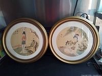 Both framed circular silk paintings side by side showing matching gilt frames