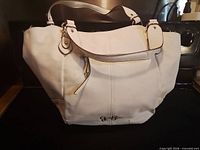 Front view showing white perforated exterior, zipper pocket, logo emblem, dual handles