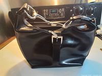 Full exterior view of black leather hobo bag with silver hardware