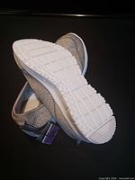 View of soles and side profile showing white flexible outsoles and grey uppers