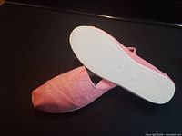 Side and sole view of one flat atop the other showing color and unworn sole
