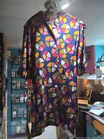Full view of longline geometric print shirt jacket hanging, showing pattern, length and button front