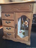 Full view of jewelry armoire showing drawers, glass door with floral panel