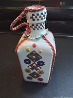 Front view of leather-wrapped glass decanter showing appliqué patterns and stopper