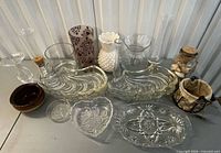 All items laid out together showing variety of glass dishes, vases, jars, ceramic crock and rope-net holder