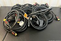 Pile of nine black HDMI cables with visible connectors