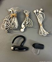 All five audio accessories laid out: two Bluetooth headsets and three sets of wired earbuds