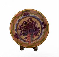 Front view of ceramic plate on stand showing floral artwork and border