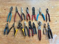 Full layout of 14 pliers and snips on wooden surface