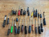 Overview of all screwdrivers and scraper laid out on workbench