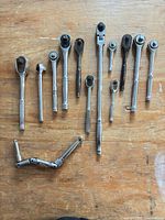 Full layout of thirteen ratchets and flex handles on wooden surface