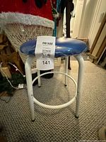 Full view of stool showing blue seat and white frame