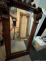 Front view of carved wood cheval mirror showing ornate crest, dark finish, intact glass