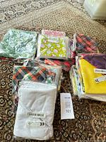 Multiple sealed packages of assorted bandanas and fabric squares on rug