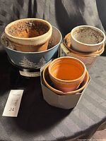 Group of nested pots showing blue metal winter pot, grey hexagonal planter, orange terracotta pot and others
