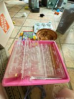 Full lot showing plastic candy molds in pink tray, copper fish mold, cookbook, mini cake pan