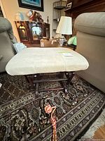 Front view of ottoman showing wood glider base and upholstered top
