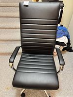 Front view of black faux leather high-back office chair showing ribbed upholstery and padded armrests