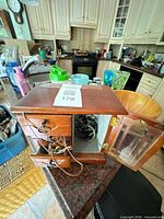 Overall view of open brown wood jewelry box on counter showing drawers, glass door and jewelry inside