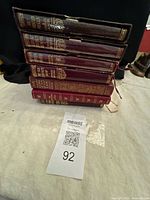 Stack of six burgundy leather-bound volumes showing gilt spines and slipcase