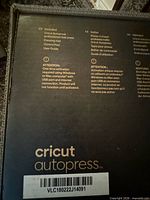 Close-up of box panel listing contents: Cricut Autopress professional heat press, pressing mat, control pod, user guide