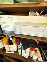 Front view of Cricut Maker 3 retail box on shelf with vinyl rolls below