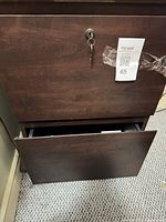 Front view showing dark brown veneer two-drawer cabinet with lock and key inserted