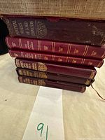 Stack of six burgundy leather books showing gilt spines and wear