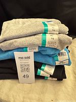Stack of folded Gildan T-shirts in three colors with tags visible