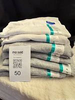 Stack of six folded Gildan T-shirts with tags visible, one white on top, five gray beneath