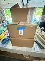 Two cardboard boxes with wrapped glass jar and wooden lid placed on top
