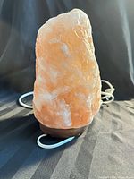 Front view of Himalayan salt lamp showing crystal color and wood base