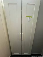 Front view of closed white two-door wardrobe with handles visible