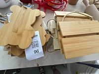 Stack of bamboo flower/cloud cut-out plaques alongside three-slat bamboo pallet signs with jute hangers