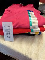 Stack of folded T-shirts showing pink, red, black layers