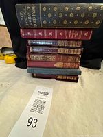 Stack of eight assorted vintage books showing bindings and gilt tooling