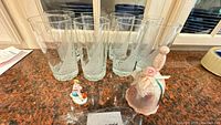 Lot overview showing eight etched glasses, pink bell, small figurine