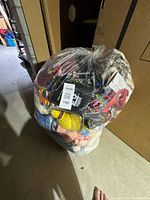full view of sealed clear bag filled with plush toys and blankets