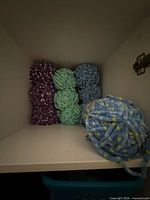 Shelved chenille yarn balls in purple speckled, mint, aqua, blue, yellow-blue stripe