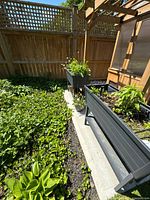 Both charcoal resin planters situated in garden showing overall condition and size reference