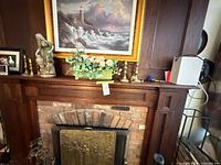 Mantel view showing porcelain figurine, brass candlesticks, floral arrangement, owl, small pink trinket